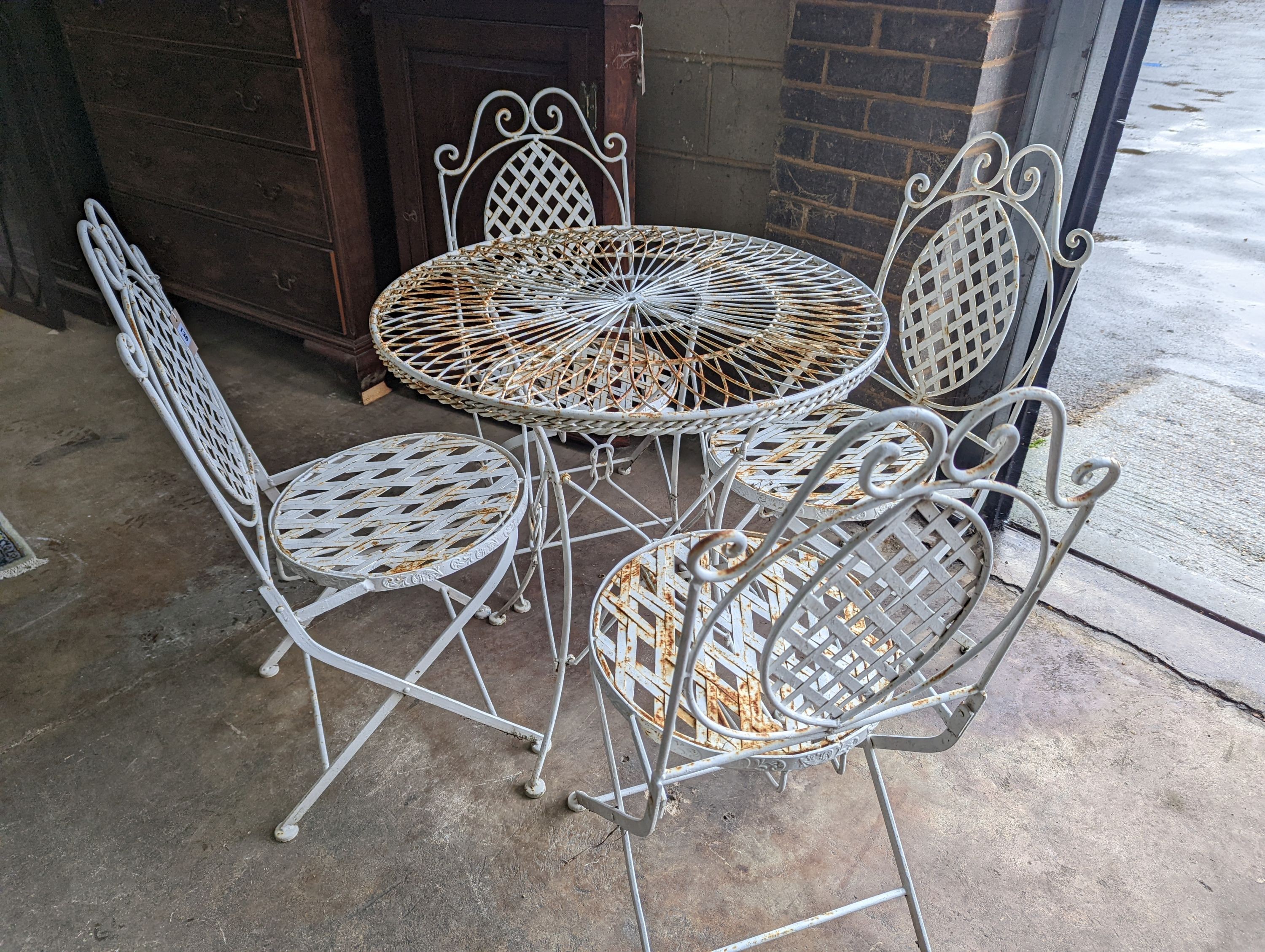 A circular painted wrought iron garden table, diameter 75cm, height 75cm together with four painted wrought iron folding garden chairs